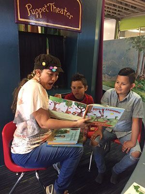 Woman reading a book to two young boys.
