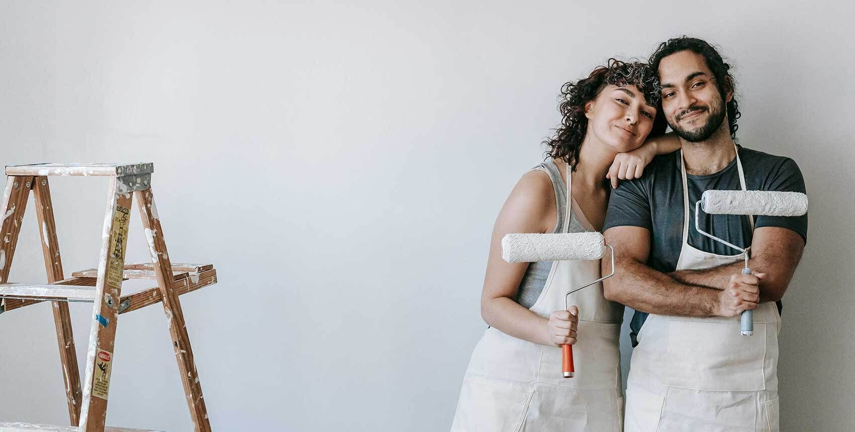 Two people holding paint rollers