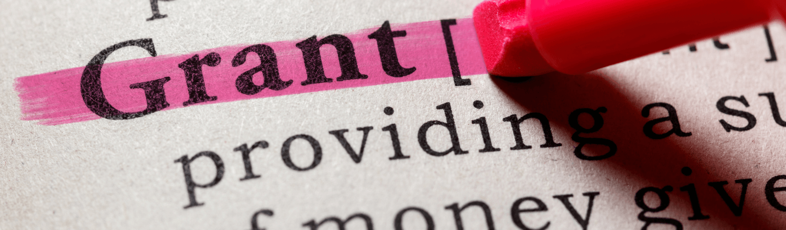 Image of person with pink highlighter, highlighting the word "grant" on a paper.