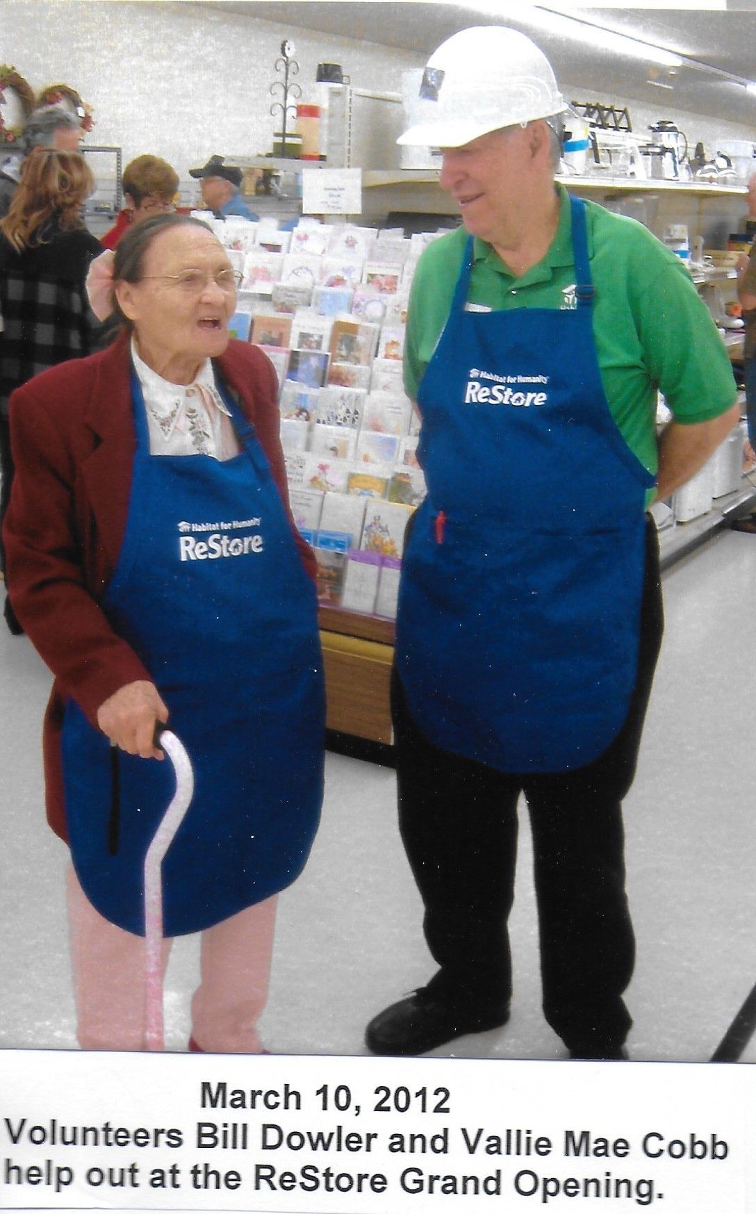Volunteer Bill Dowler stands in a ReStore apron with another volunteer. 