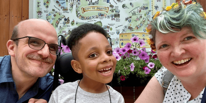 a Caucasian couple smiling with their adopted African American son