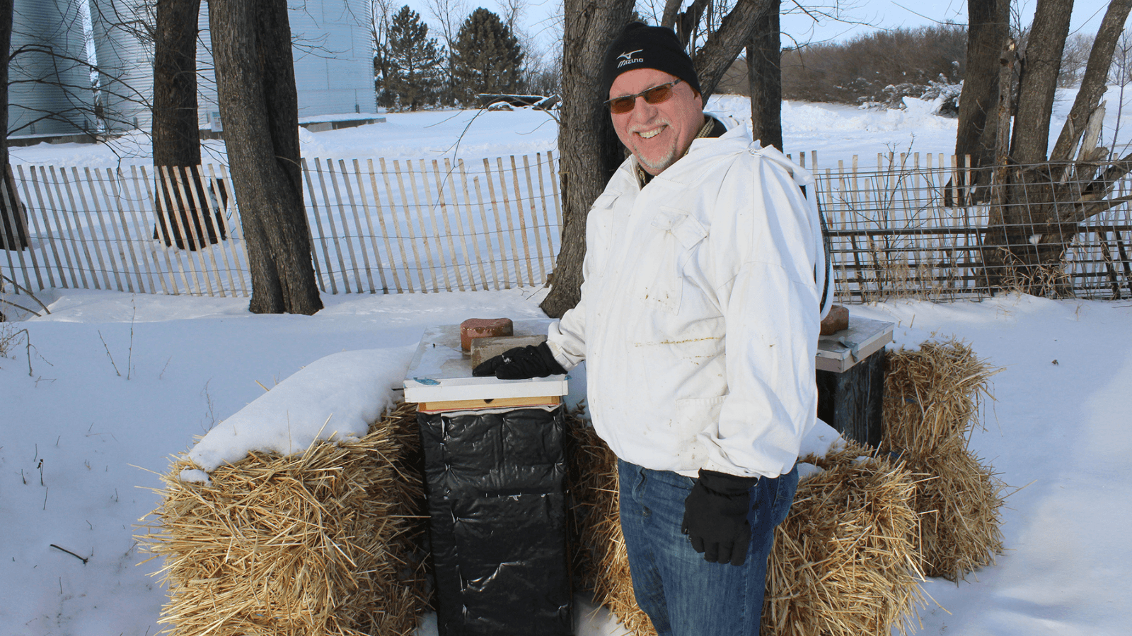 Beekeeper standing in front of beehive with bees