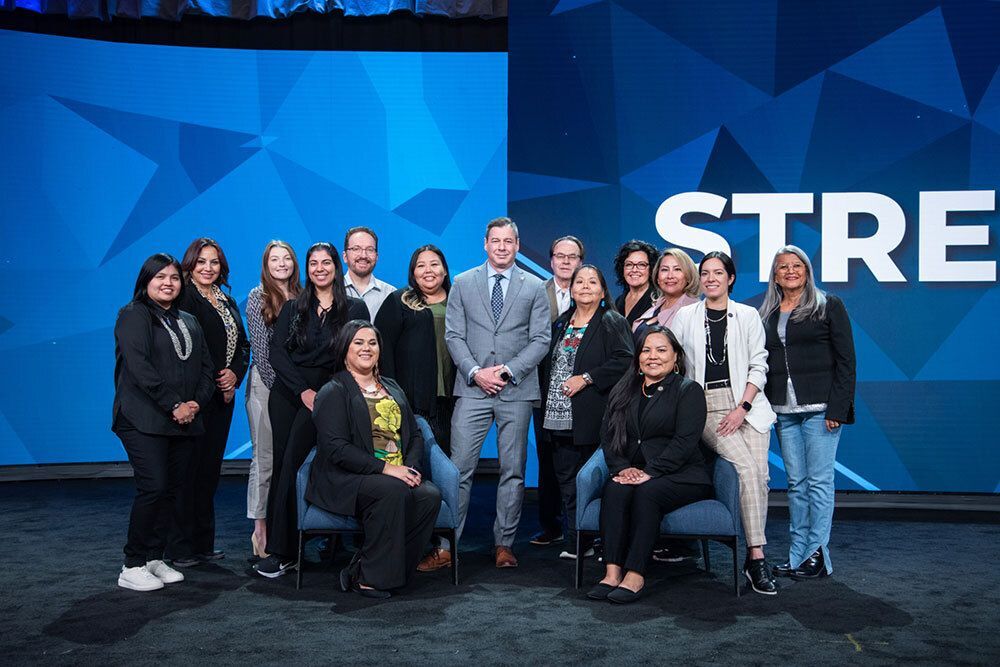 A group of 15 people from the National Center for American Indian Enterprise Development, some sitting and some standing while dressed in business attire.