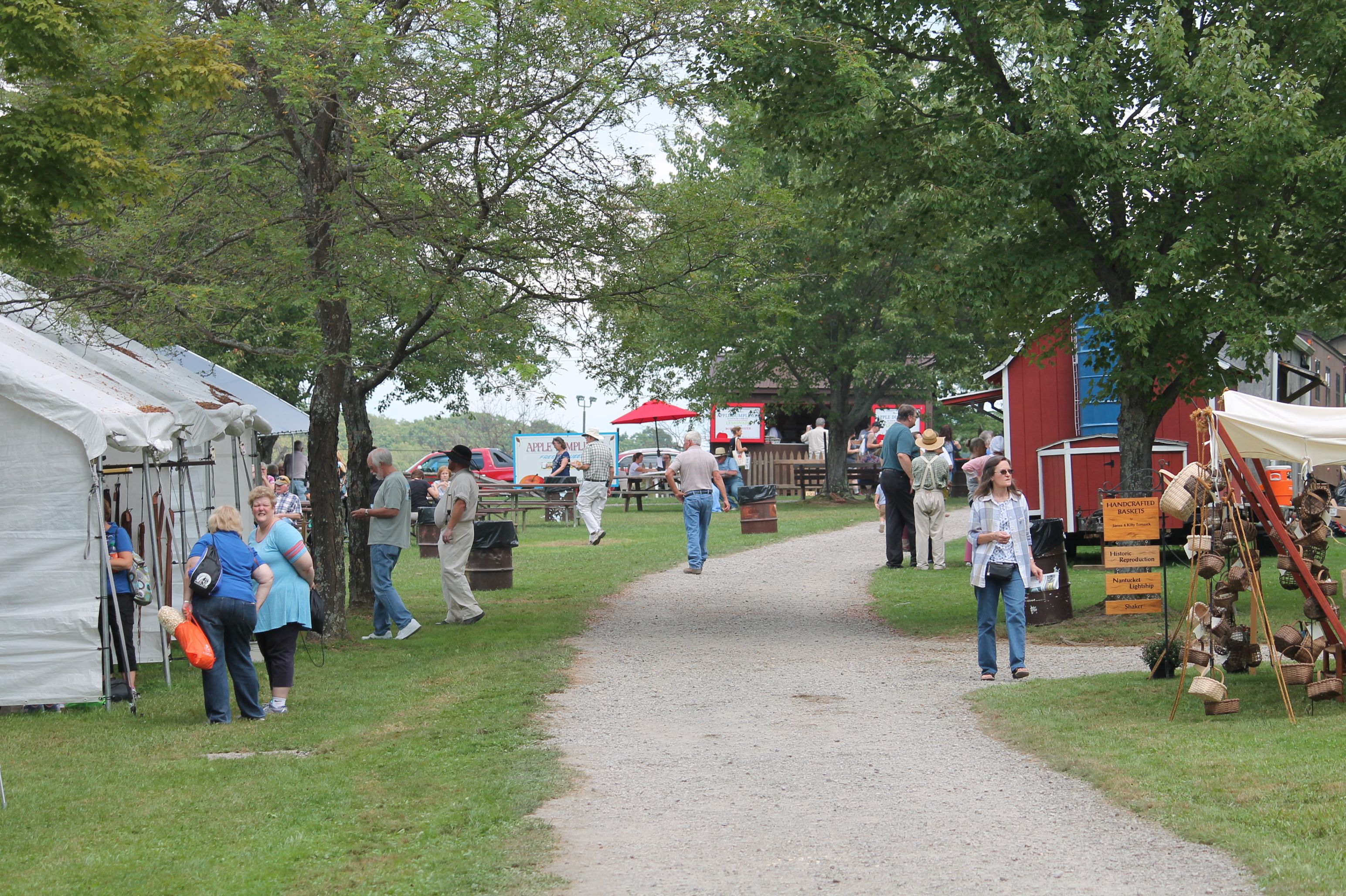 Crowd outdoors at Mountain Craft Days with tents along a gravel path.