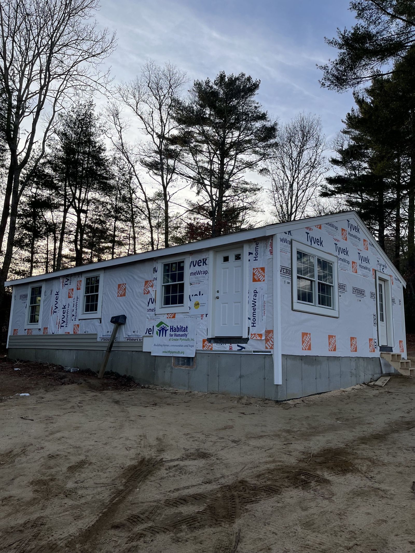 Photo of full house exterior showing new windows and doors installed with TYVEK wrap and no siding yet