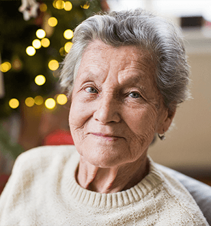 Older woman sits by holiday background looking at the camera with dignity