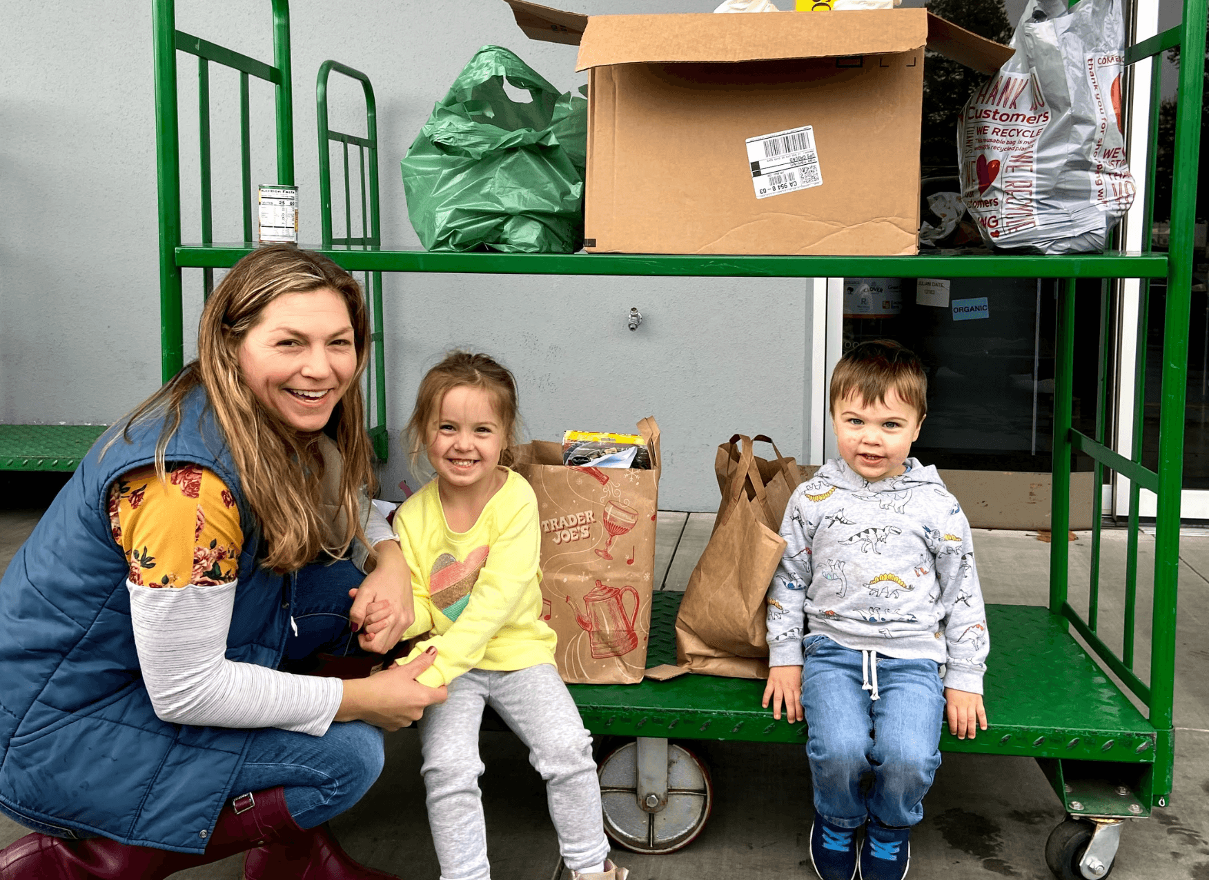 Photo of a young boy in the hatchback of the car carrying out bags of food to donate