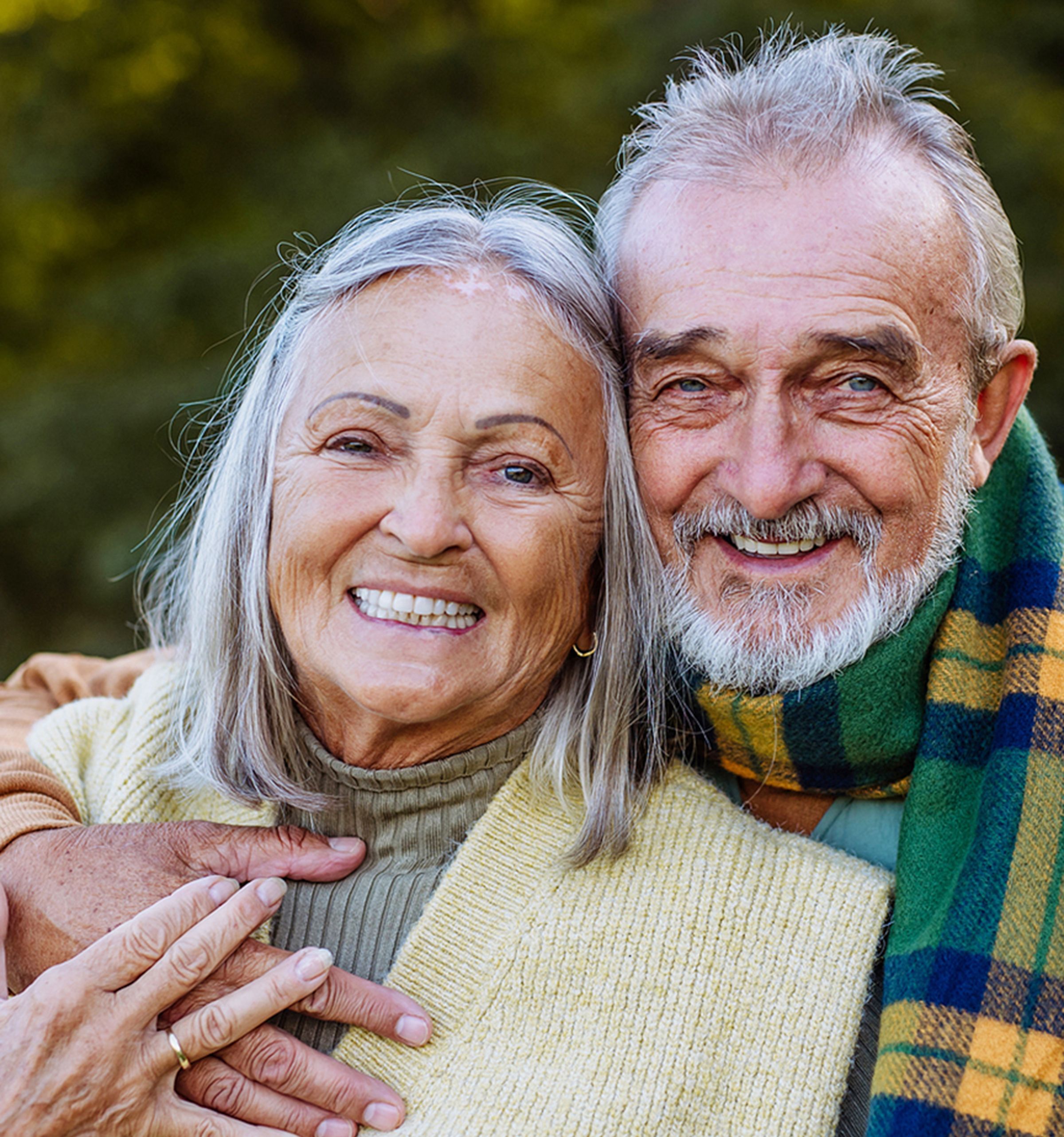 Older woman smiles with senior man in the fall