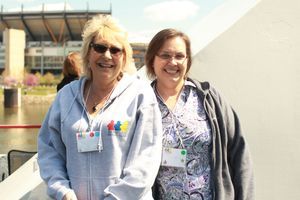 Two women stand side-by-side smiling at the camera. The woman on the left is wearing a grey PSC Partners sweatshirt.