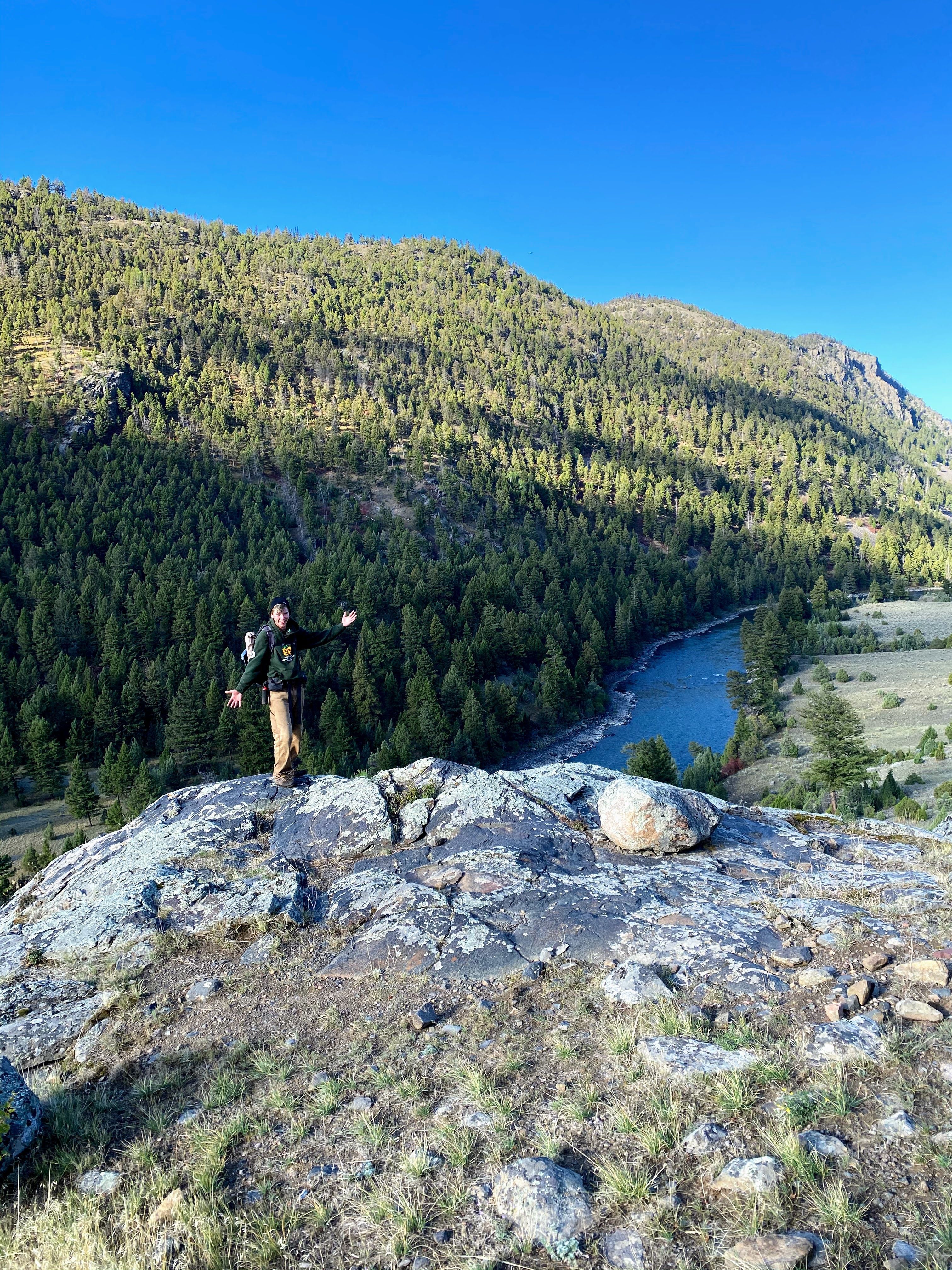 A crew member stands on an overlook above a river