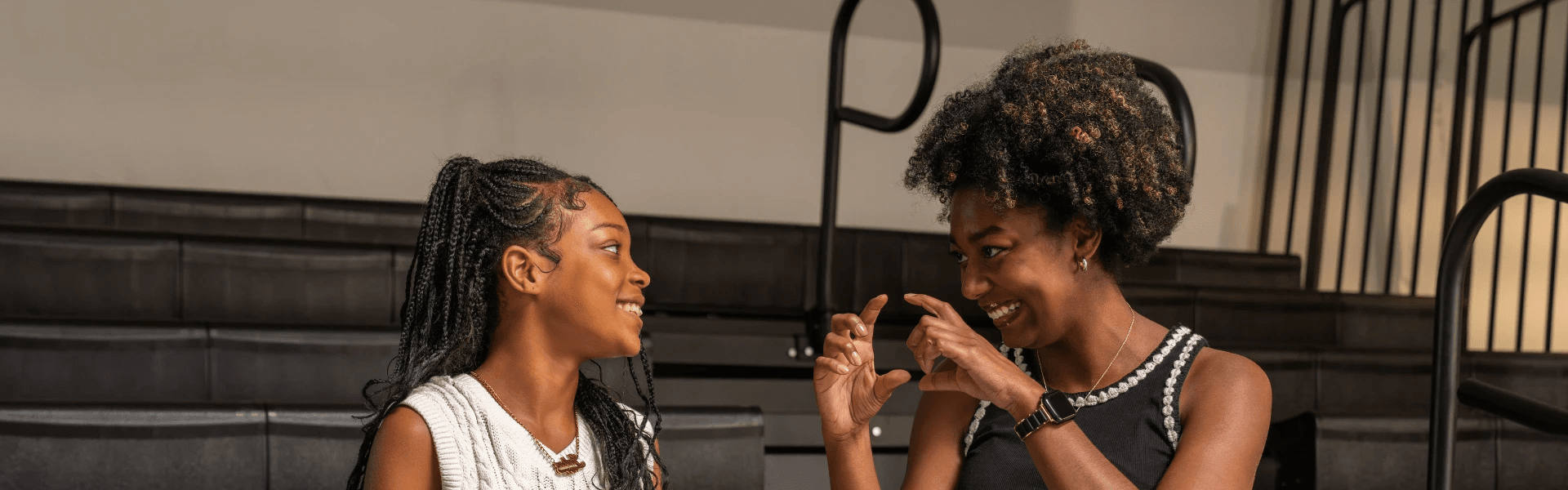 A Big Brother and Little Brother from Big Brothers Big Sisters of the Midlands sit together at a table playing chess, smiling at the camera and enjoying quality time during their mentoring session.