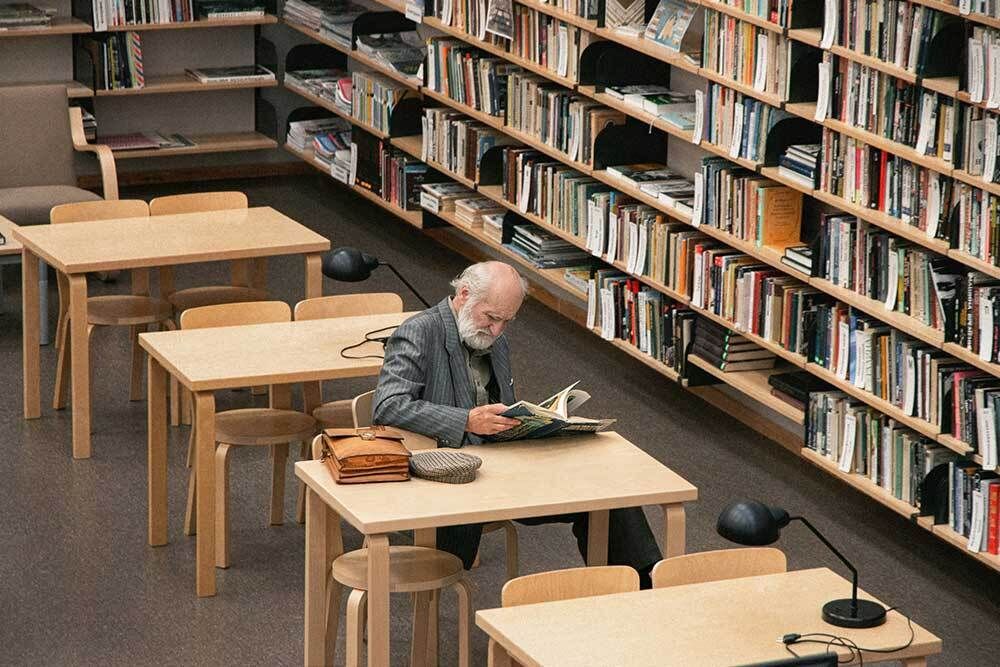 Man Seated at a Table Reading a Book