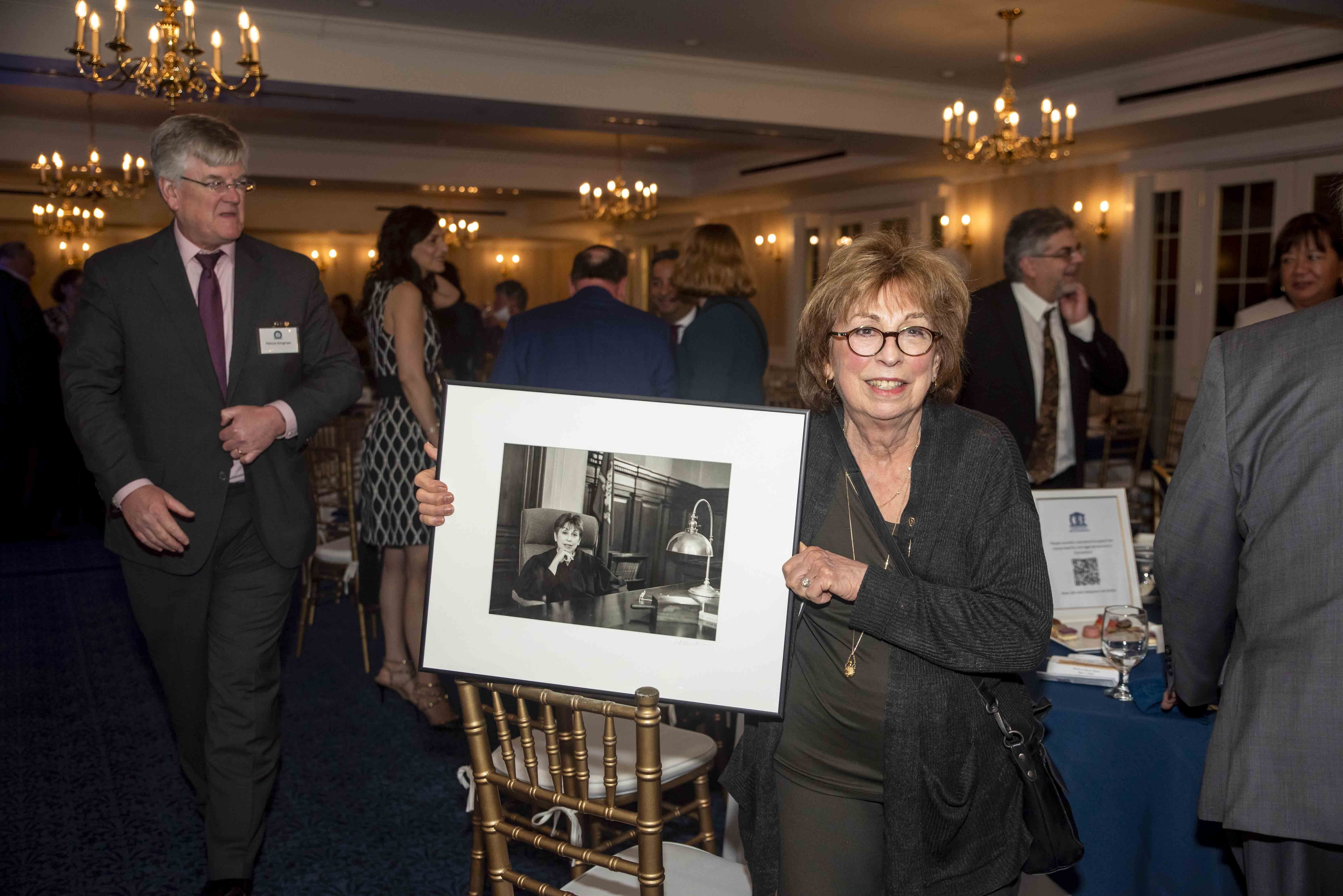 Image of Judge Peck holding a photograph of herself serving the State of Connecticut.