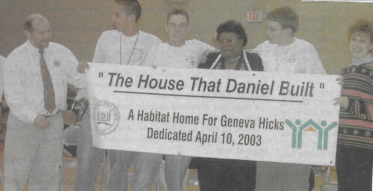 Homeowner Geneva Hicks poses with D.W. Daniel High School students holding a banner that reads "The House that Daniel Built".