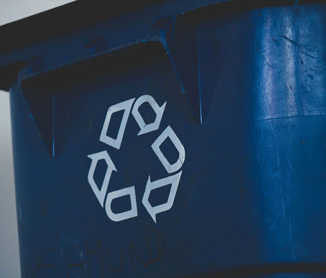 Close-up of a blue recycling bin with a white recycling symbol.