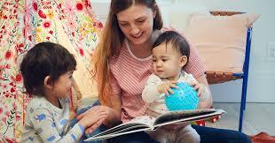 a mother reading a book with her small children