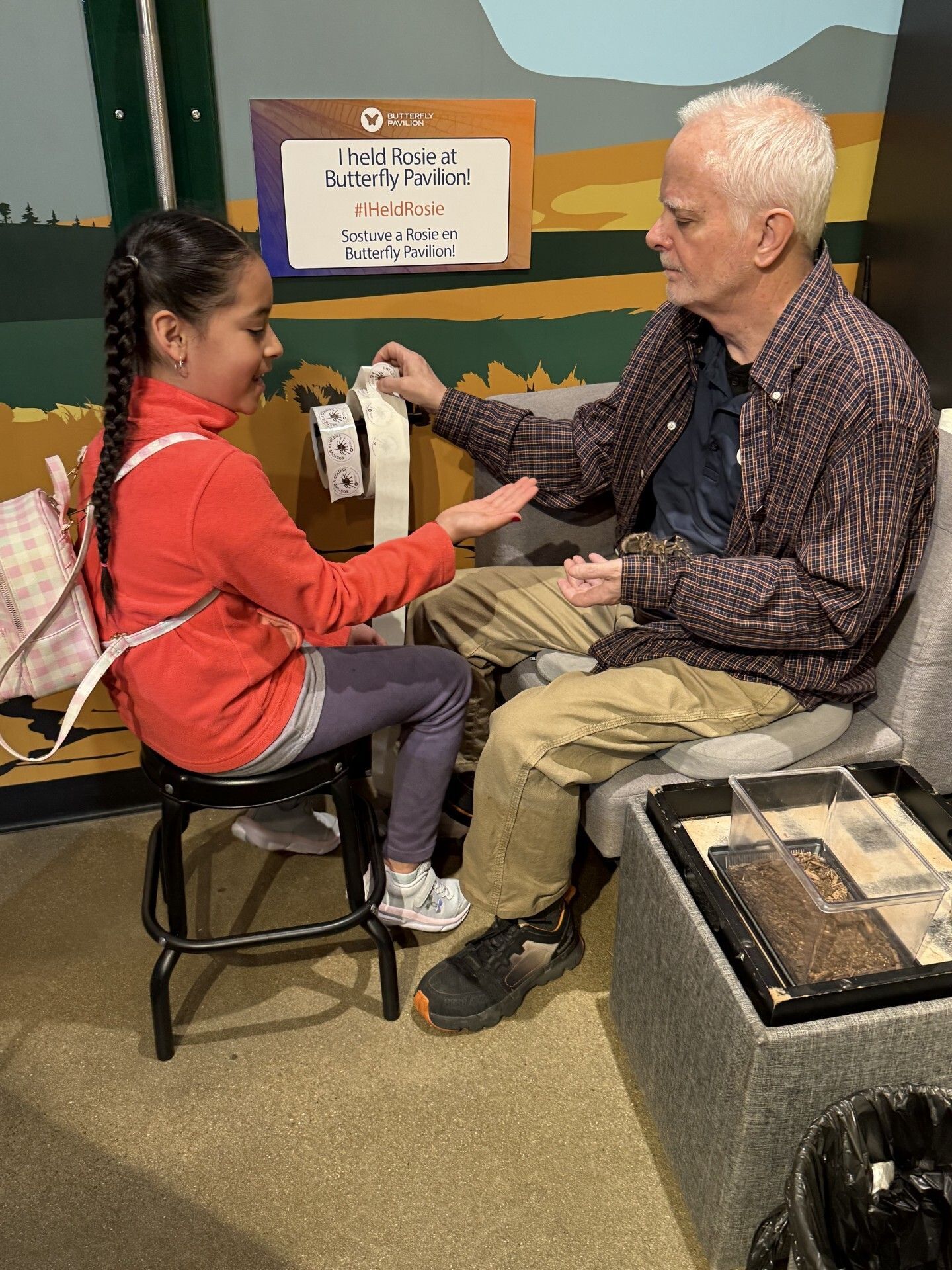 A young student gently holds Rosie, a tarantula, during an educational visit to the Butterfly Pavilion.
