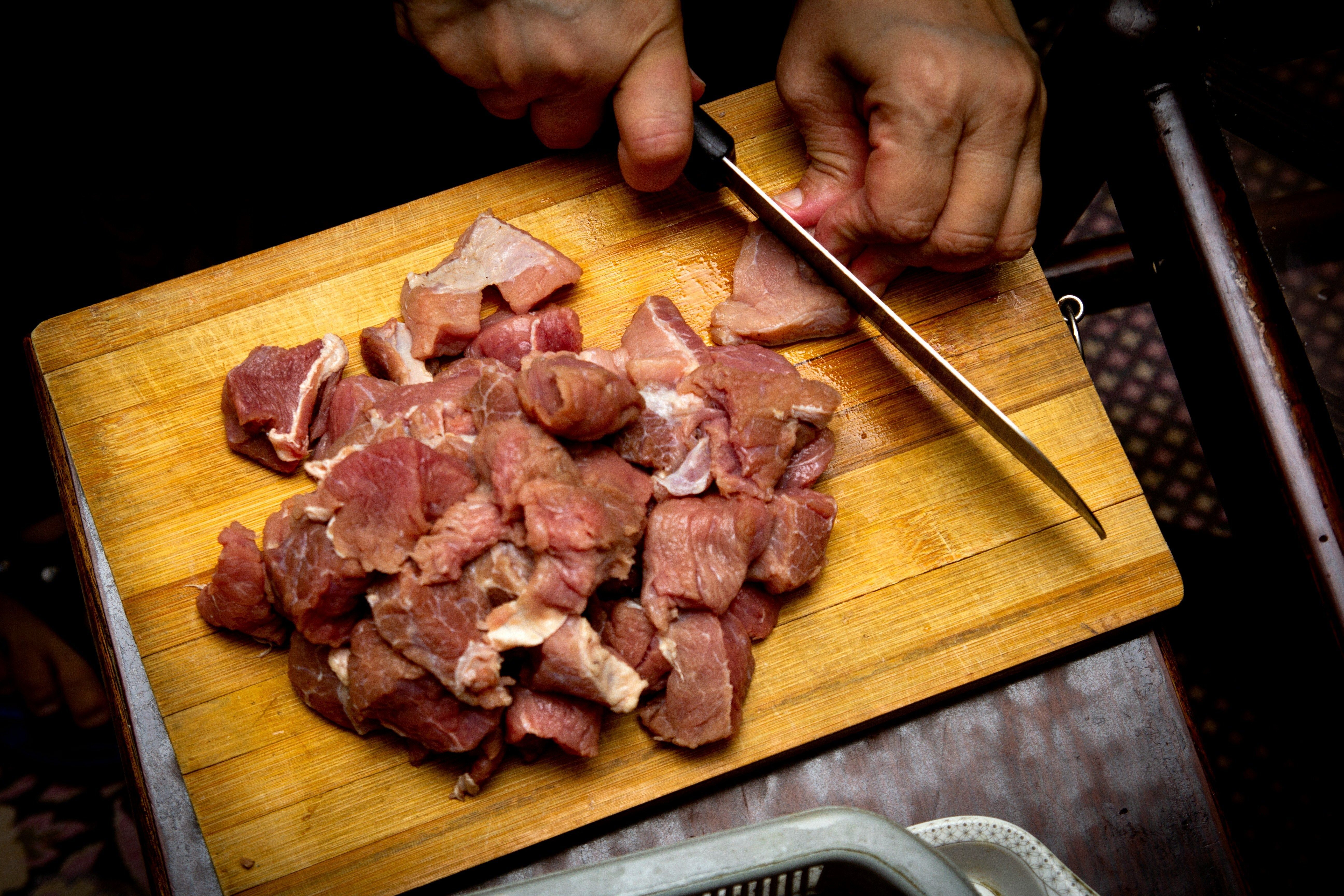 Meat being cut with a knife on a cutting board