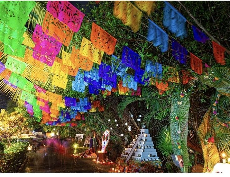 Colourful papel picado banners hanging above a Day of the Dead altar.