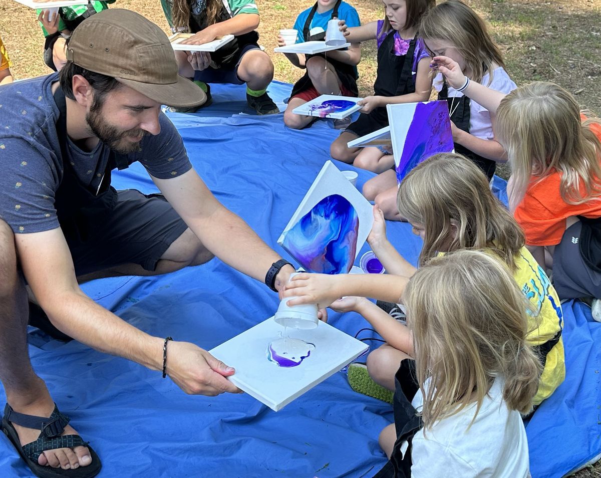 An educator helping a camper paint their masterpiece during Amazing Artists Camp.