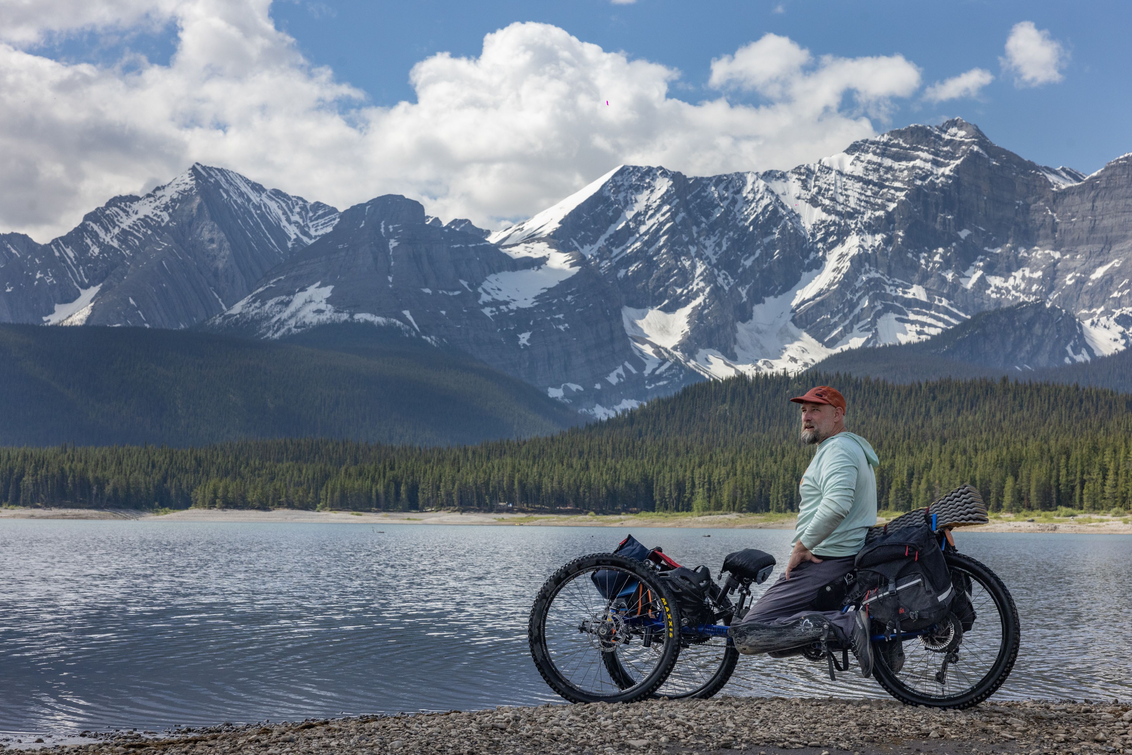Man sits up in an adaptive hand-cycle with mountains in the background