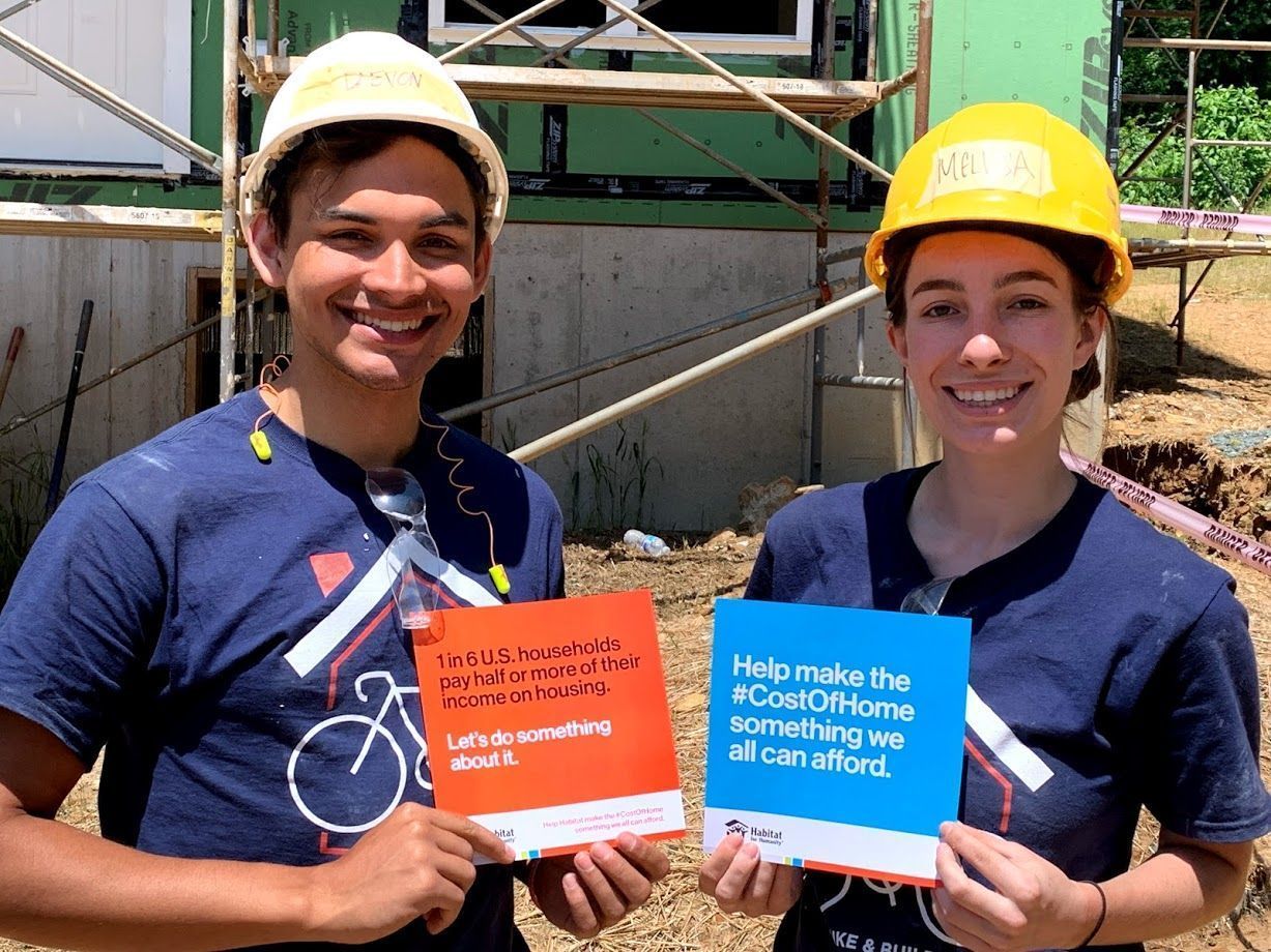 Man and woman smiling and holding Habitat for Humanity flyers.