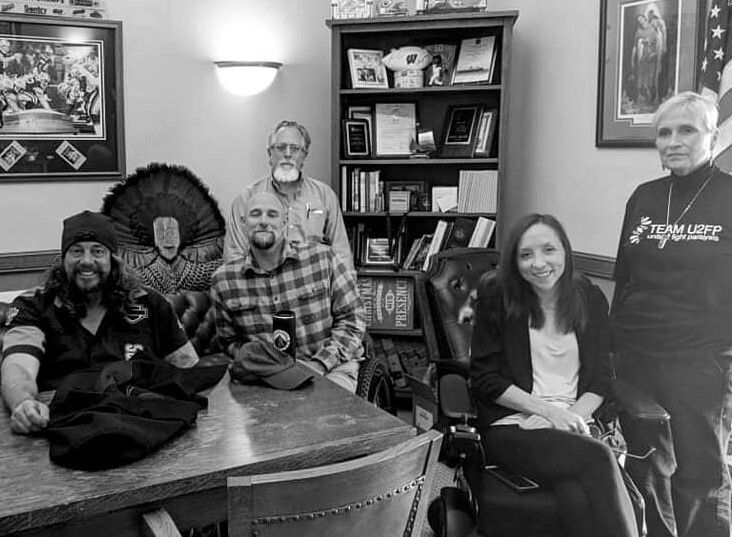 three white men and two white women face the camera - three are in wheelchairs