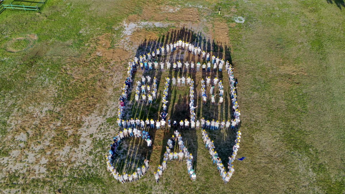 Arial vision of people forming a house icon and the Care-A-Vanners initials