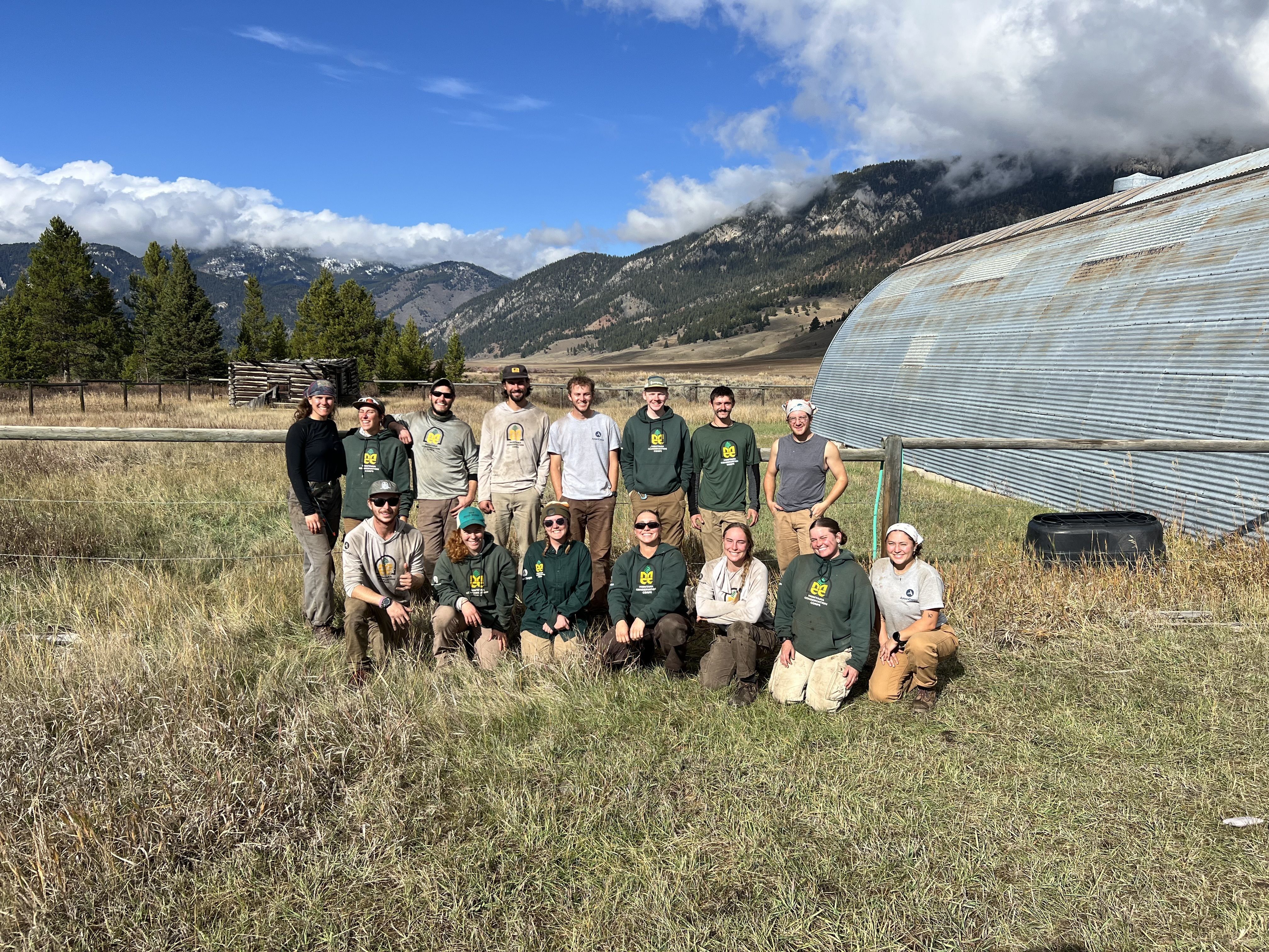Two crews sit smiling next to their shelter.