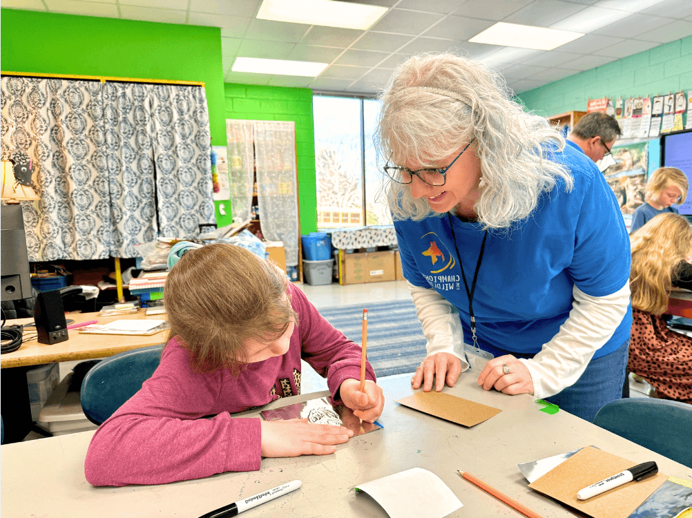 Volunteer helping a student create jeweled foil art
