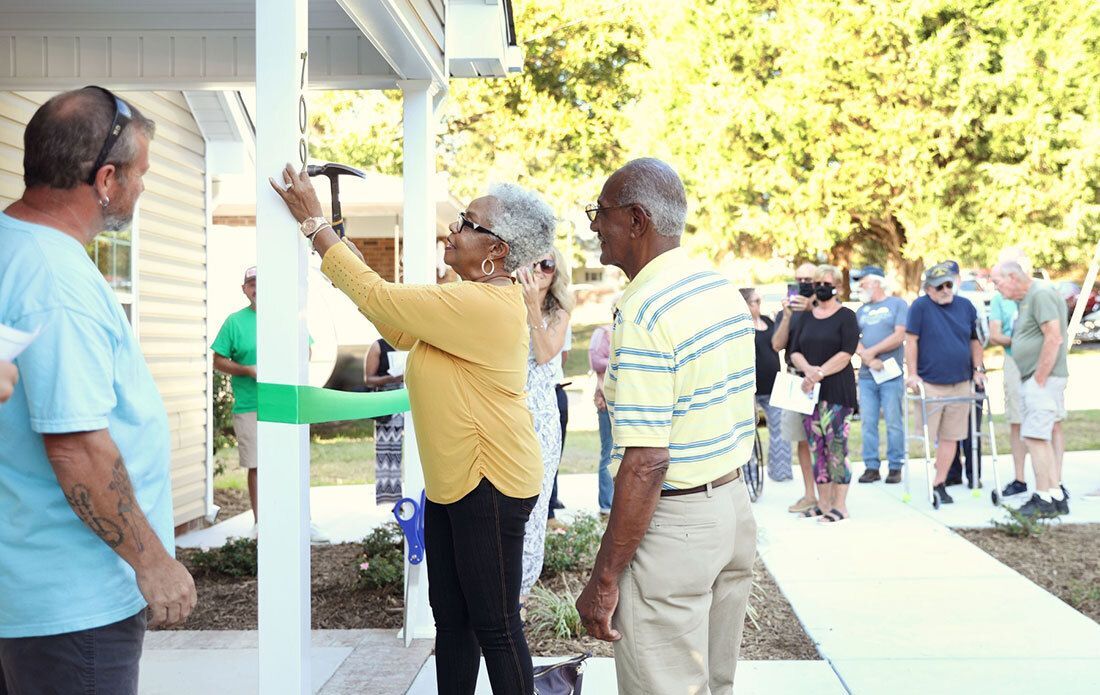 Woman hammers house numbers to new habitat home during dedication ceremony.