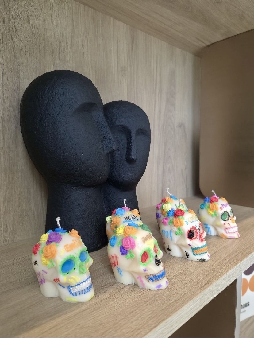 Sugar skull candles decorated with colourful flowers and painted details.