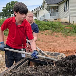 Volunteers shoveling mulch into a wheelbarrow