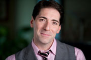 Nicholas Viselli, A man is wearing a pink collar shirt with a vest and a tie. He is also smiling for the picture.