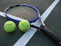 A tennis racket lying on a court next to two balls.