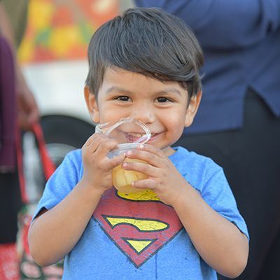 Young boy with a very big smile holding apple sauce