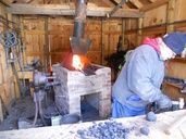 Person working in a wooden workshop with a glowing forge.