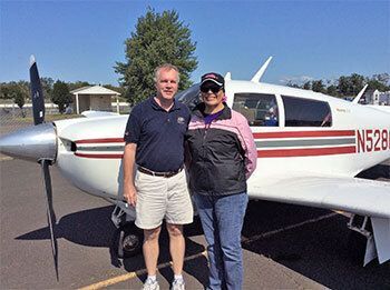 Ken & Gina Lewis in front of an airplane.