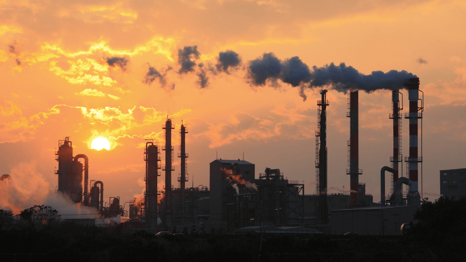 Power plant emitting smoke at sunset