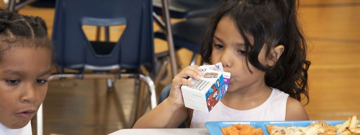 two elementary students eating lunch in a school cafeteria