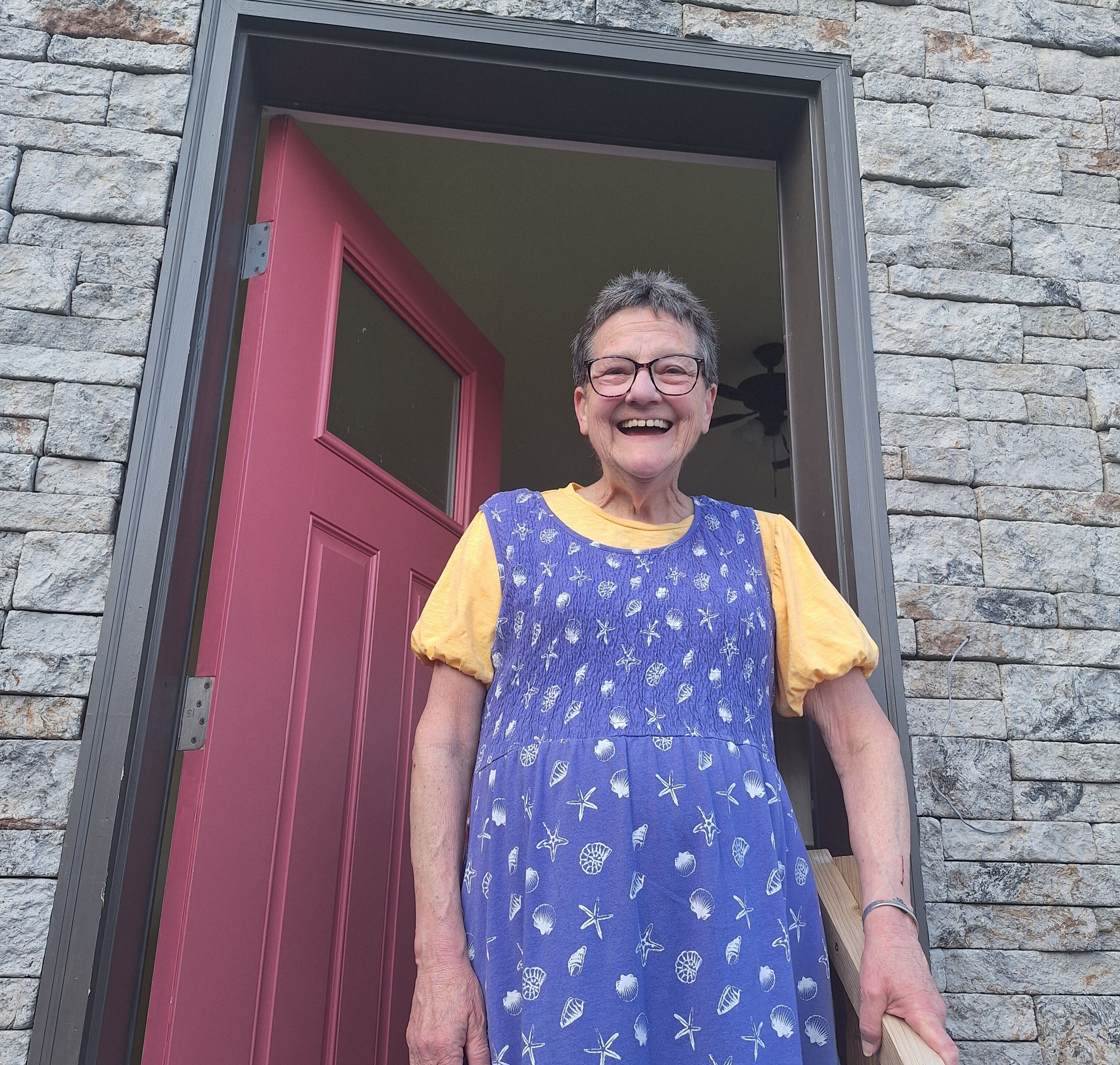 Trilby standing in front of her pink front door.