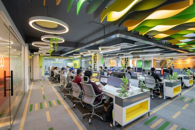 Open workspace using colorful, sound-absorbing ceiling baffles to mitigate ambient noise and visually support a cohesive office branding strategy.