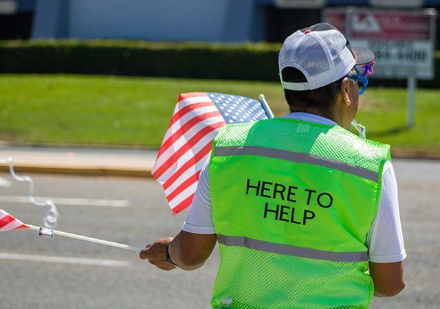 Volunteer wearing a bright yellow vest that says Here to Help.