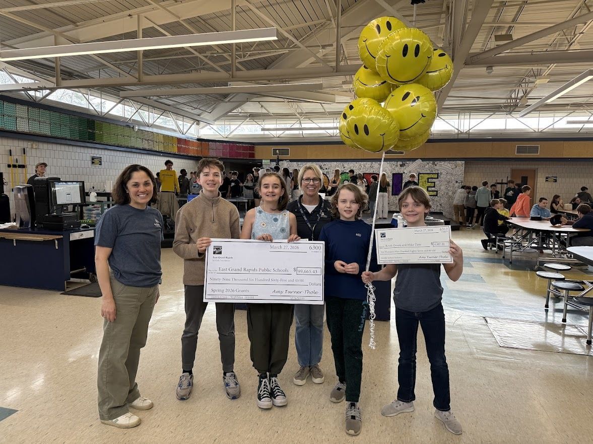 Foundation board members with students holding big checks and balloons