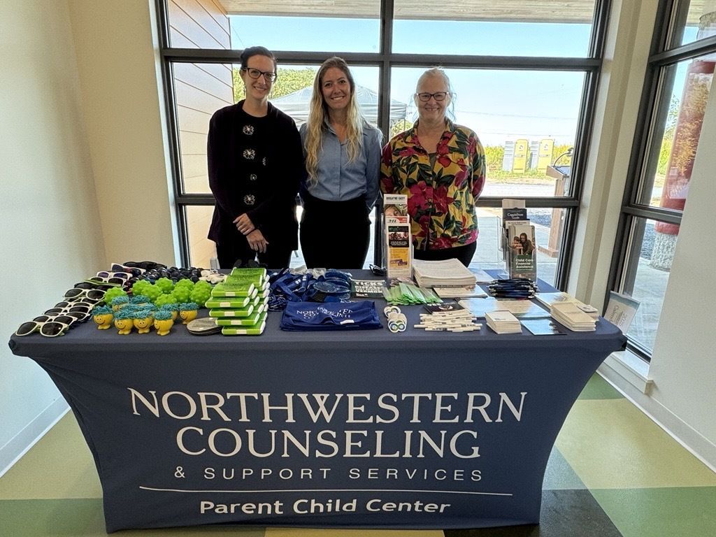 Three people standing being a table display from Northwestern Counseling & Support Services