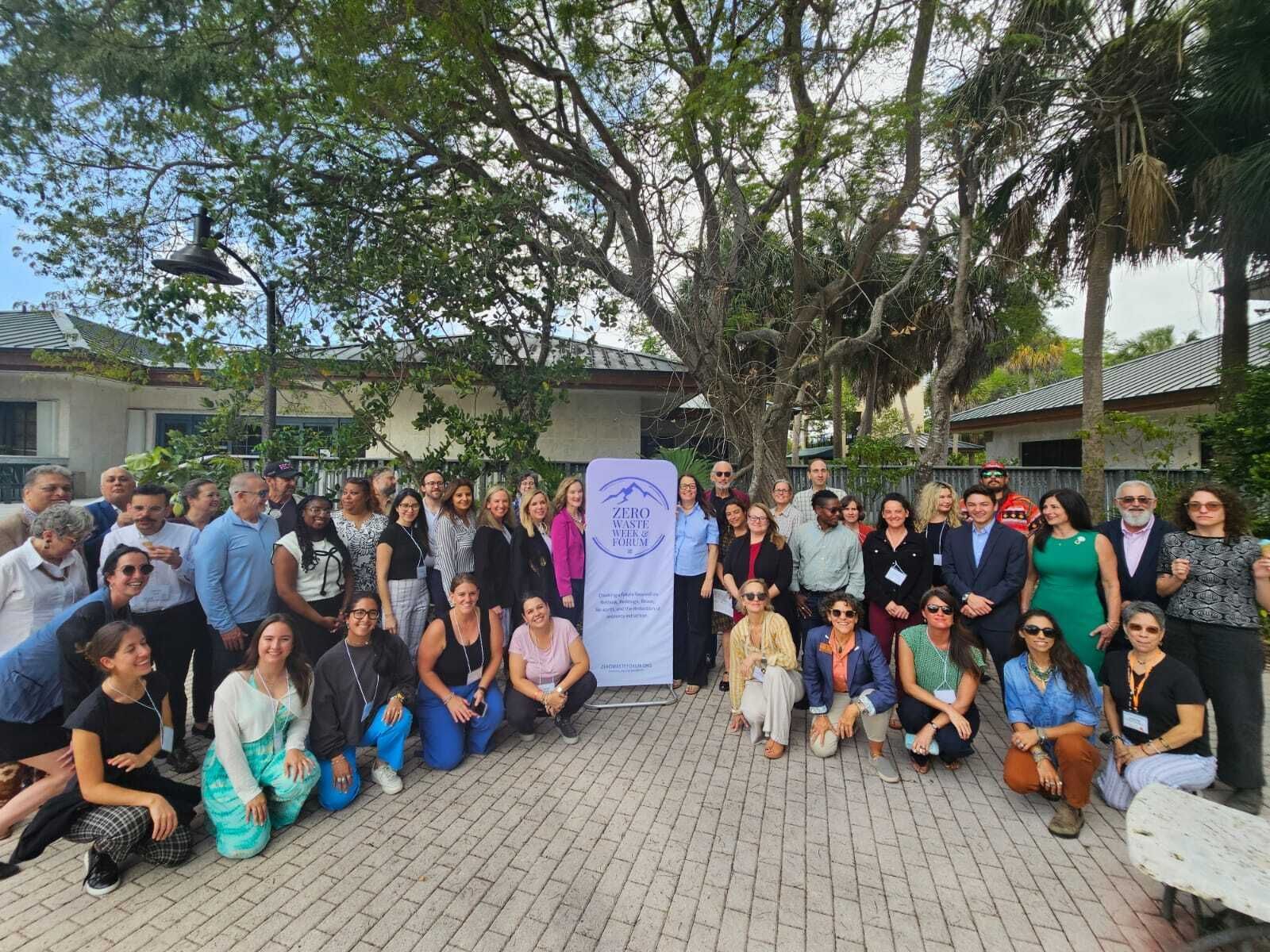 Group picture of Zero Waste Forum Day 2 attendees at the Anne Kolb Nature Center, with the light purple Forum banner in the center. 