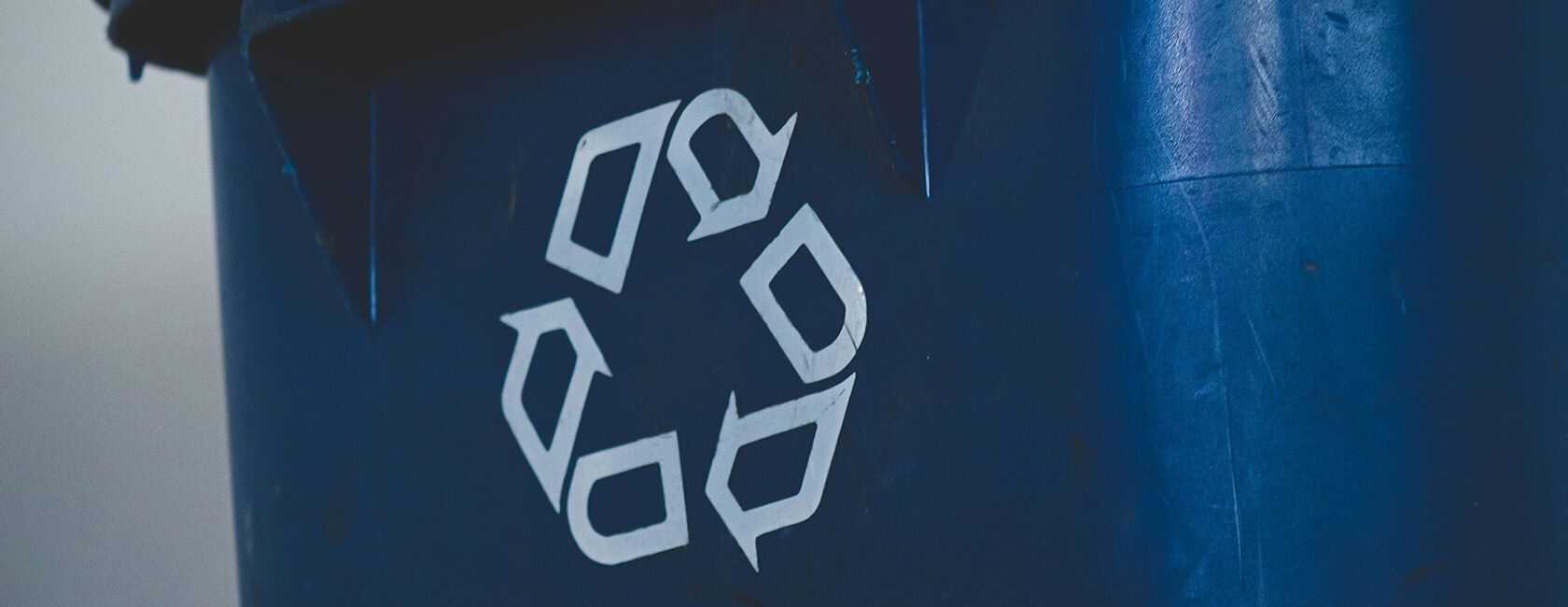 Blue trash can with recycling logo on it.