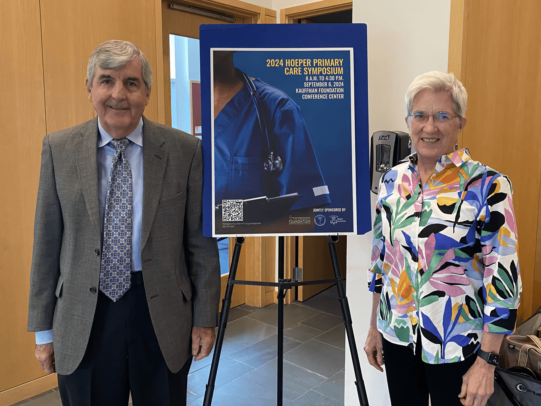 two physicians posing by symposium sign