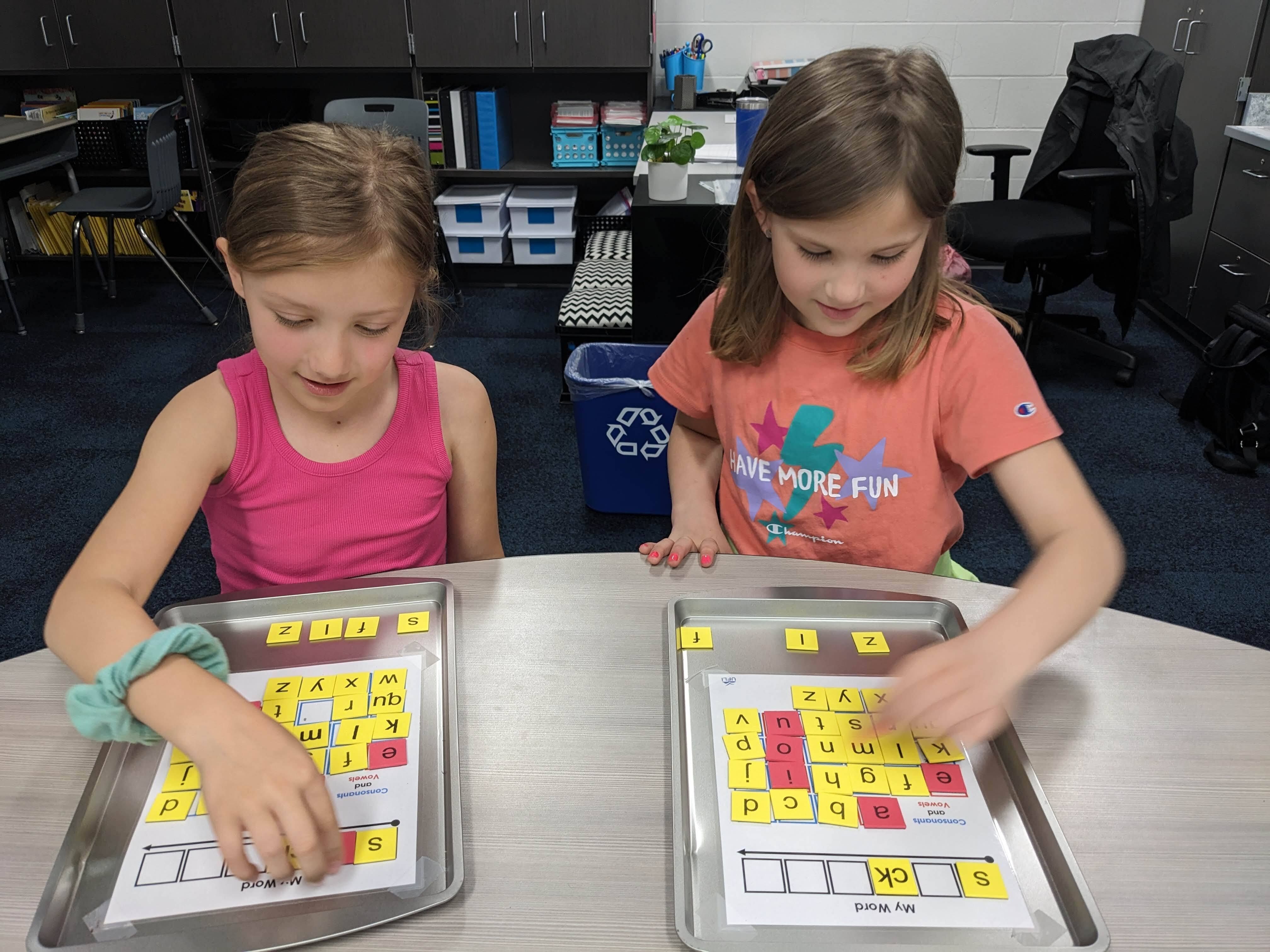 First grade students working on phonics skills with magnetic tiles.