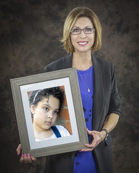 Woman holding a picture of a child.